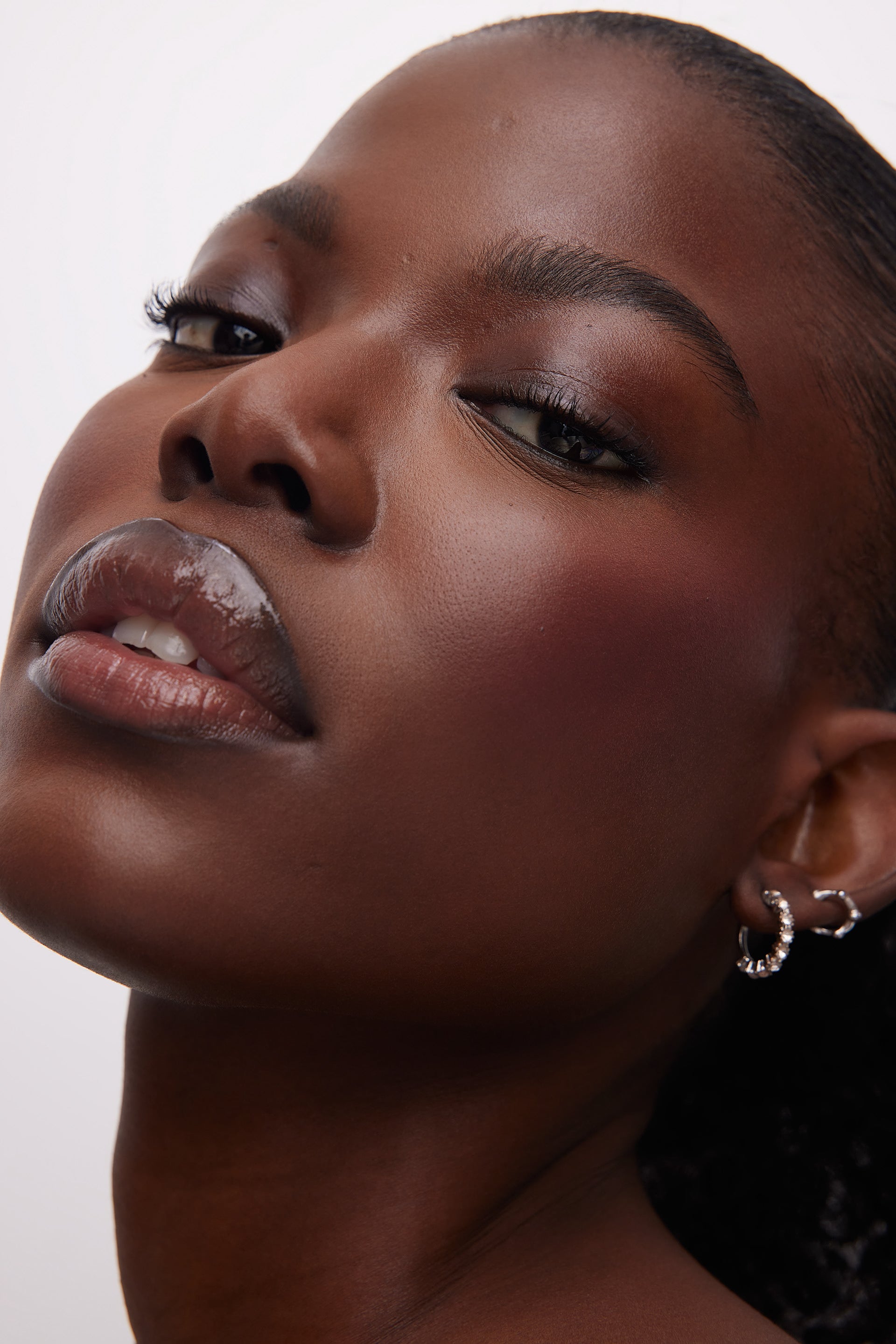 Close-up of a woman's face and earrings with a neutral background
